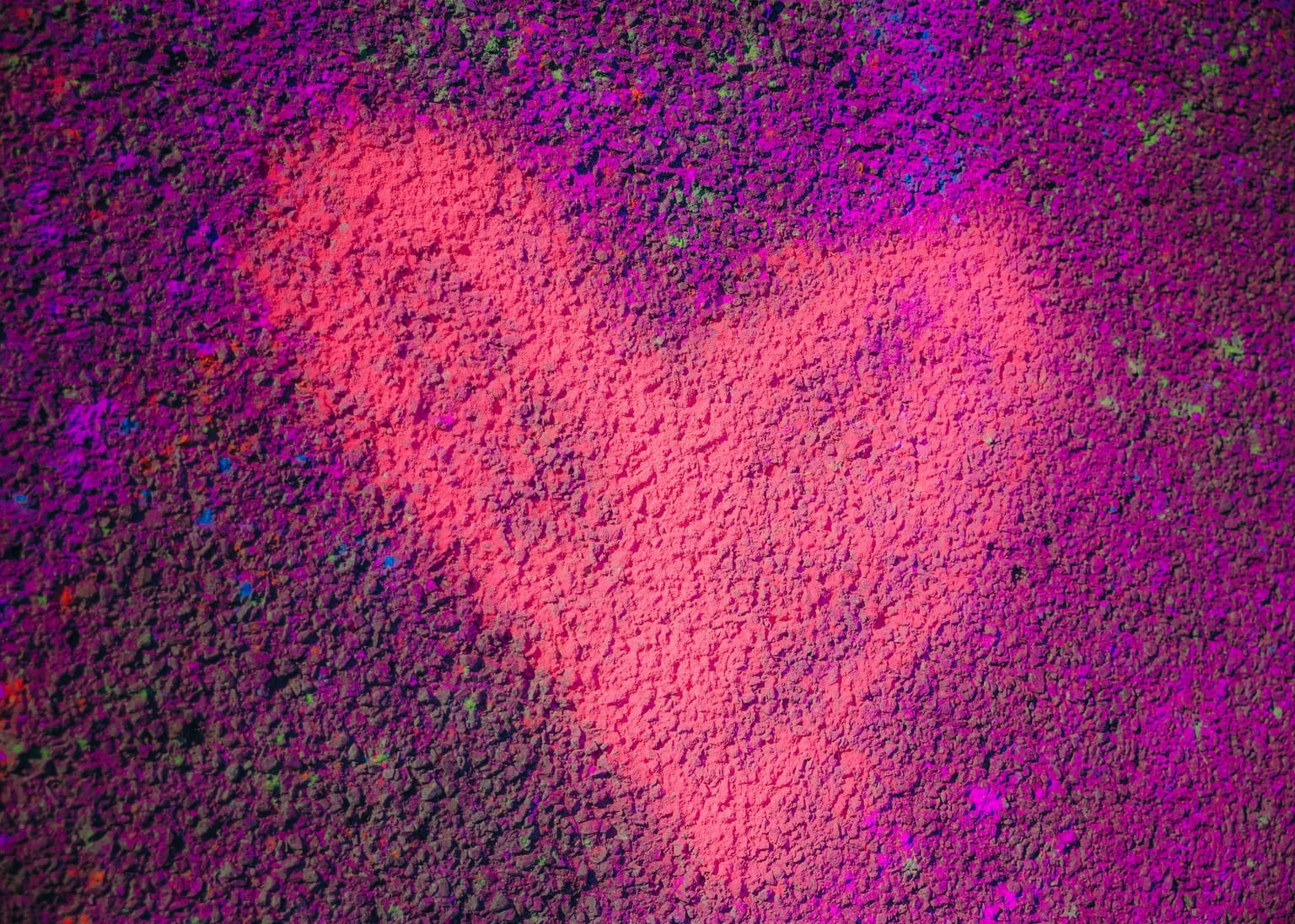 A heart drawn in bright pink powder on purple-dusted asphalt at the CCHSC Color Run.